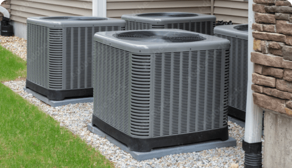 row of residential AC units outside a home with a brick wall and brown siding