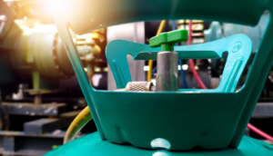 Close-up of a green refrigerant tank valve in a mechanical setting, with a focus on the valve handle. The image emphasizes the importance of checking for refrigerant leaks to ensure efficient HVAC system performance and prevent potential hazards.