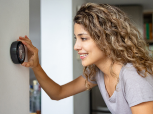 Woman adjusting the temperature at home using a smart thermostat stock photo