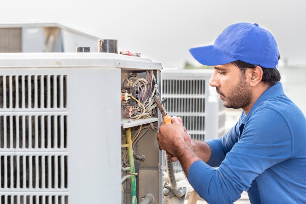 A professional electrician is fixing the heavy air conditioner