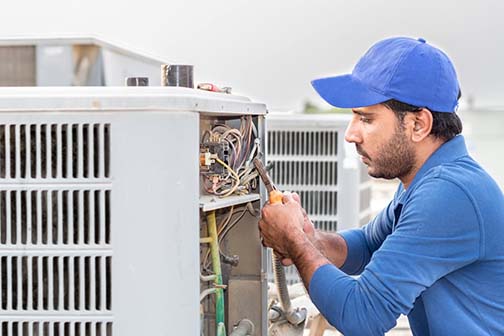 A professional electrician is fixing the heavy air conditioner