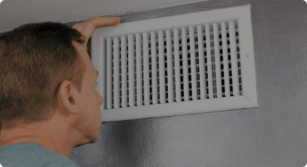image of a man in his 50's looking at his HVAC vent for dust or dirt