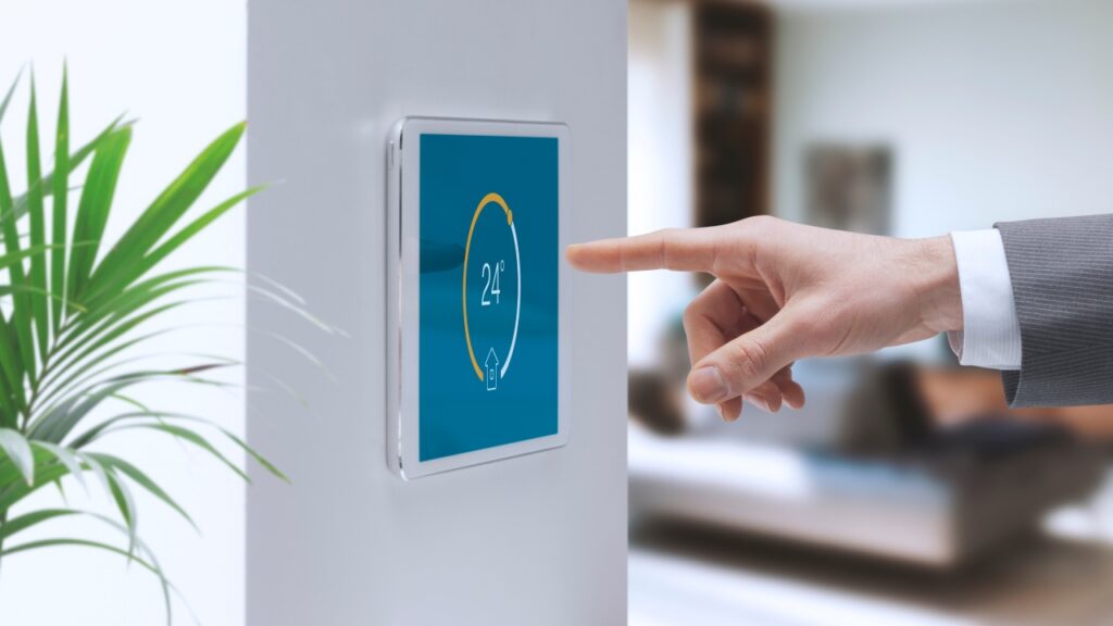 A person adjusts the temperature on a digital wall-mounted thermostat in a modern, well-lit room. Residential AC Replacement
