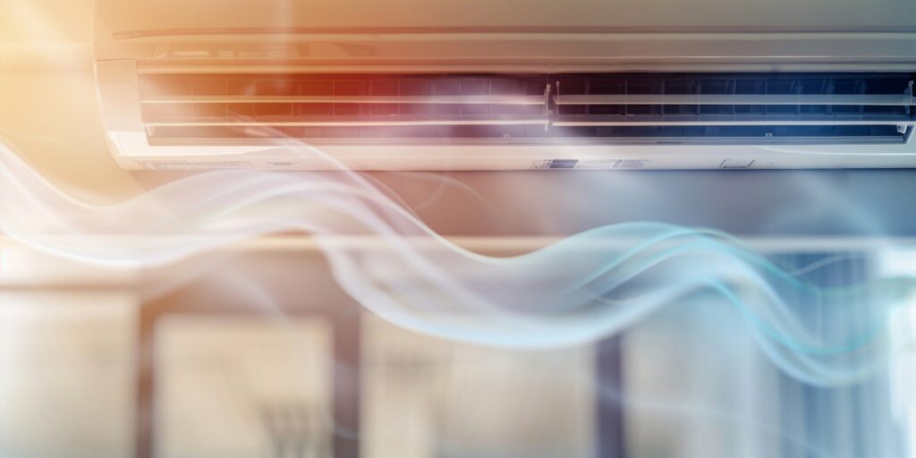 Close-up of a wall-mounted air conditioner blowing cool air, with visible airflow represented by wavy lines.